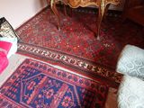une pièce avec une table, une chaise, un tapis et d'autres objets posés par terre