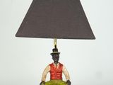 une figurine représentant un homme assis sur une chaise sur laquelle est posée une lampe