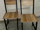 two wooden chairs sitting next to each other on a tile floor