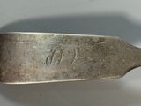 a silver spoon with a handle on a white surface
