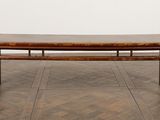 a wooden bench sitting on top of a wooden floor next to a white wall