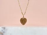 un collier avec un cœur en or et une chaîne, sur fond rose
