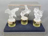 three glass figurines of birds sitting on top of a blue box