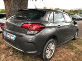 the rear end of a grey car parked next to a tree