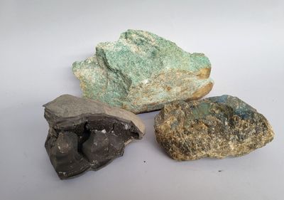 trois pierres de couleurs différentes posées les unes à côté des autres sur une surface blanche
