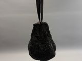 un sac à main noir orné de perles, suspendu au bras d'un mannequin