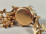 a close up of a gold bracelet with a clock on it