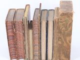 several old books stacked on top of each other on a white surface