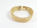 gros plan d'un bracelet en or sur fond blanc