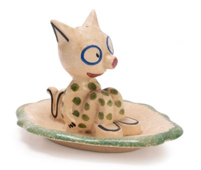 a small ceramic figurine of a cat sitting on a plate