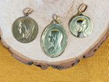 three silver and gold medals of jesus and mary on a wood slice