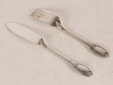 two forks and a knife on a white table