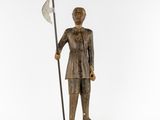 a wooden statue of a man holding a spear and a flag