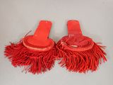pair of red sandals with fringes on them sitting on a white surface