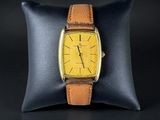 a close up of a watch on a pillow on a black surface