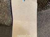 a close up of a person ' s hand holding a tag with the word sessun on it
