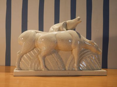 une sculpture en céramique représentant deux chevaux et un chien, posée sur une table