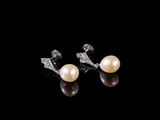 une paire de boucles d'oreilles en perles et diamants sur fond noir
