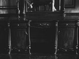 black and white photograph of a woman standing in front of a mirror
