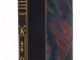 an old book with a black cover and gold trim