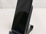 a black cell phone sitting on a stand on a white surface
