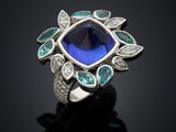 a close up of a blue sapphire and diamond ring on a black surface