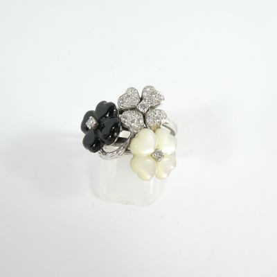 un gros plan d'une bague posée sur une surface blanche, avec des fleurs noires et blanches