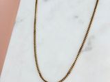 un collier à chaîne en or posé sur une surface en marbre