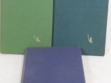 three books are lined up in a row on a white surface