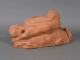 an image of a clay figurine of a man laying on a rock