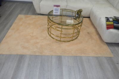 une table basse avec un plateau en verre posée sur un tapis dans un salon