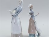 two figurines of a woman and a dog standing next to each other