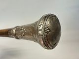 a metal object with a wooden handle on a white surface