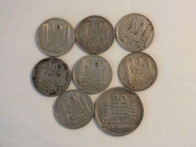 six silver coins sitting on top of each other on a white surface