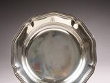 an antique silver plate on a stand on a white surface