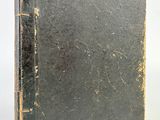 an old book sitting on top of a table next to a white wall