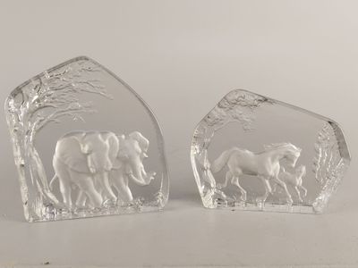 une paire de serre-livres en forme d'éléphant en verre transparent posés sur une surface blanche