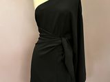 a black dress on a mannequin stand with a white background