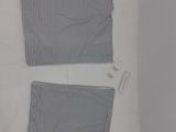 two pieces of clothing on a bed with a tag on it