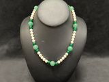a green and white beaded necklace on a mannequin