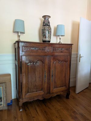 a wooden cabinet with two lamps on top of it