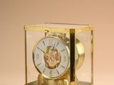 a small gold clock with a glass case on top of it