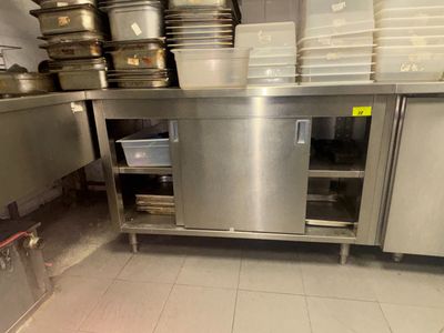 une grande cuisine en inox avec beaucoup de vaisselle sur le plan de travail