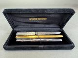 two pens in a case on a table with a white table cloth
