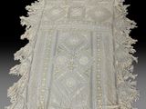 un chemin de table en dentelle blanche ancienne à franges sur fond noir
