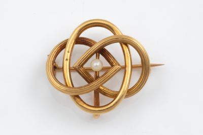 a close up of a gold brooch with a pearl in the center