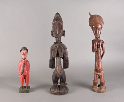 trois figurines en bois de formes et de tailles différentes posées sur une surface grise