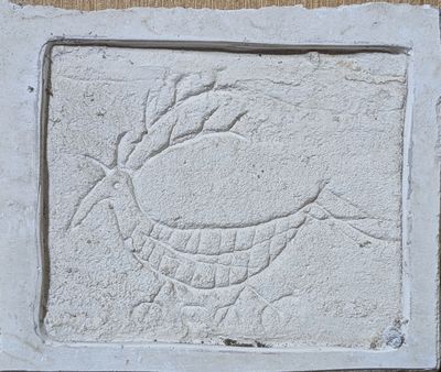 relief représentant un oiseau sur un bloc de pierre fixé à un mur