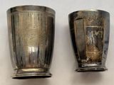 deux tasses en argent posées l'une à côté de l'autre sur une table