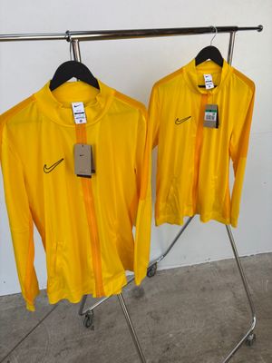 deux t-shirts jaunes suspendus à un portant dans une pièce